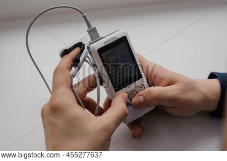 Man Using Finger Pulse Oximeter, Healthcare Monitoring Concept. Pulse Oximeter On A White Background