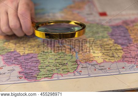 A Man Holds A Magnifying Glass In His Hand Over A Map. A Middle-aged Man With A Magnifying Glass In 