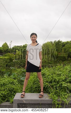 A Happy Chinese Woman Standing On A Wall With A Nature Background Within The Jinshan Temple Scenic A