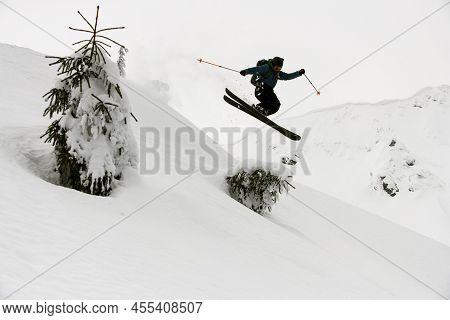 Beautiful View Of Active Skier Jumping Over Slopes Of Snow-capped Mountains