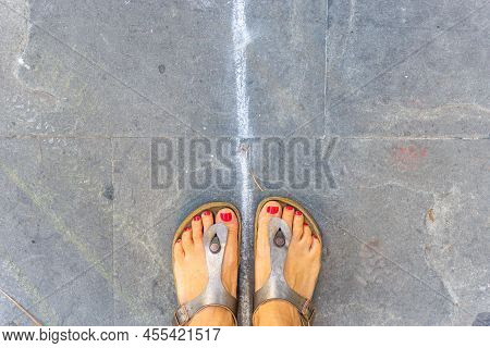 Grado, Italy - July 8, 2021: Feet In Open Sandals With Red Nail Polish On Toes