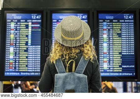 Travel People In Airport Or Train Station Concept - View From Rear Of A Blonde Curly Female Woman Wi