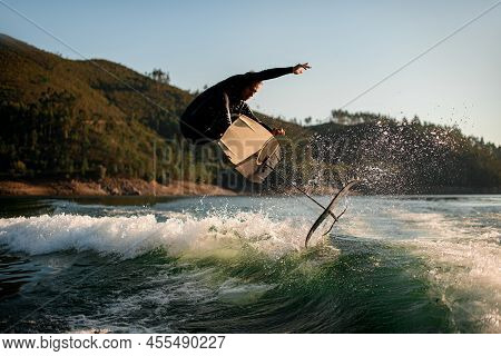 Athletic Man Jump With Foil Wakeboard Over Splashing Wave