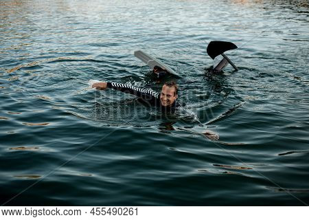 Smiling Man In Wetsuit With A Foil Wakeboard Swims In The Water
