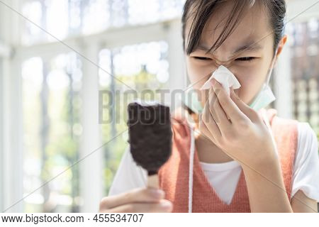 Sick Asian Child Girl Has Runny Nose And Blows Her Nose Into A Tissue Paper While Eating Too Much Ic