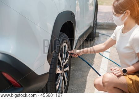 Woman Driver Hand Inflating Tires Of Vehicle, Checking Air Pressure And Filling Air On Car Wheel At 