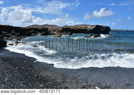 Waves Leaving The Shore Of A Black Sand Beach In Aruba.