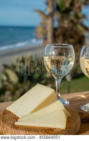 Spanish Hard Manchego, Cow, Sheep And Goat Cheese Served Outdoor With Glasses Of White Wine And View