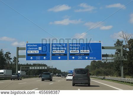 Road Sign On The Motorway And The Place In German Language As Munich City Or Nuremberg And More Cars