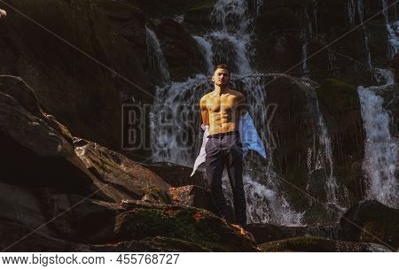 Muscular Man Going To Swim In Waterfall Water. Profit Business Concept. Businessman Undressing At Wa