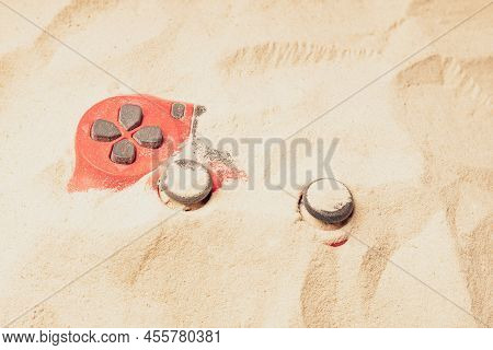 Sand And Gamepad, Red Gamepad Buried In The Sand. Buried Gaming Device