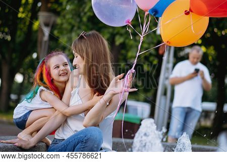 Mother And Daughter Having Fun On Girl Birthday Hugging Near City Fountain