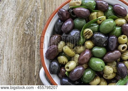 Marinated Green And Black Olives In Ceramic Bowl Over Wooden Background. Mediterranean Food.