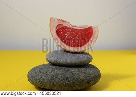 A Ballans Tower Of Grey Stones And Grapefruit Orange Fruit On A White Yellow Background With Room Fo