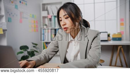 Young Asian Businesswoman Sit On Desk With Laptop Overworked Tired Burnout Syndrome At Office. Exhau