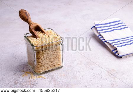Dry Risoni Pasta In A Glass Jar On A Light Background. Selective Focus.