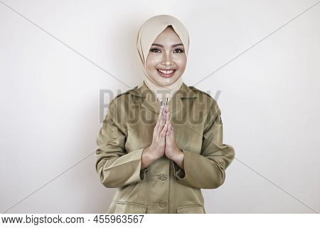 Moslem Civil Worker Wearing Brown Uniform And Hijab Greeting With A Hand Gesture And Smiling At The
