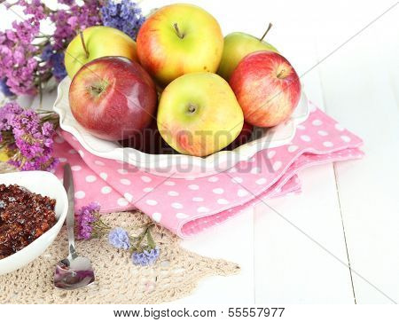 Juicy apples on plate on white wooden table