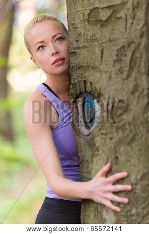 Young woman hugging a tree.