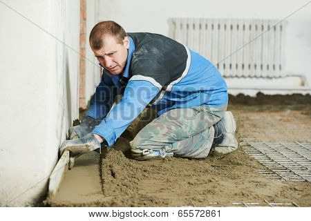 Plasterer at indoor concrete cement floor topping with float