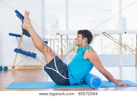Man exercising with foam roller in fitness studio