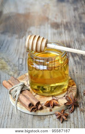 Golden honey with honeystick. cinnamon and anise stars on wooden table