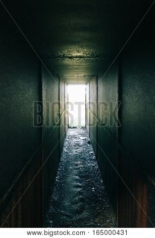 Abandoned metallic dark tunnel with daylight at the end