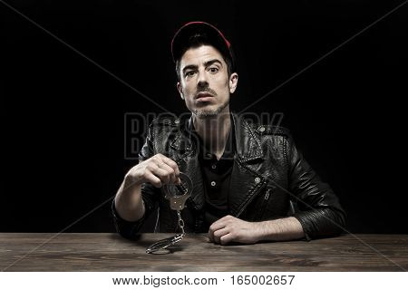 Detained young man sitting at table. Studio shot.