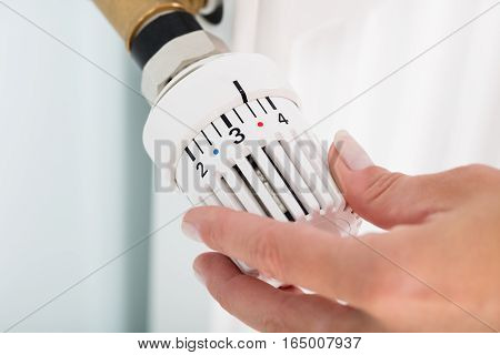 Close-up Of Person Hands Adjusting Thermostat Radiator Valve