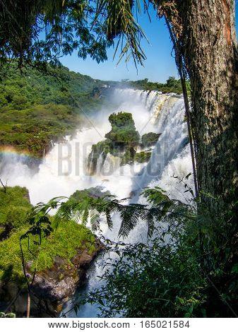 Vew of the water falls in Cataratas del Iguazu park, with a blue sky and a lot of water in the air, misty, rainow.