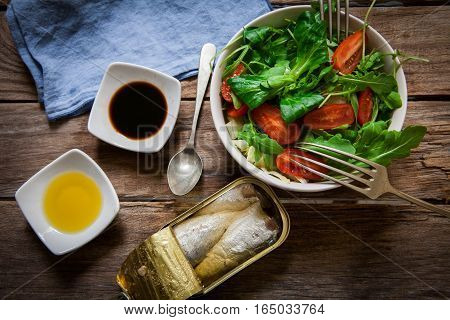 fresh mix of lettuce salad with tomato and a can of sardines in olive oil