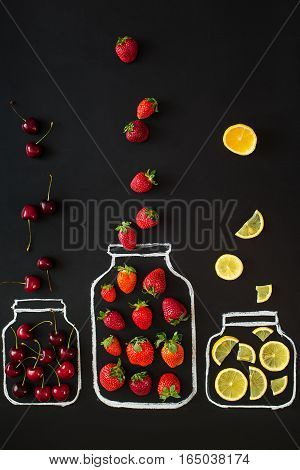 Berries and lemon with chalk pattern of jars on black bakgground. Jam cooking concept. top view, vertical