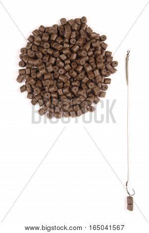 Fishing bait with hook and brown pre-drilled halibut pellets for carp fishing isolated on white background with soft shadow