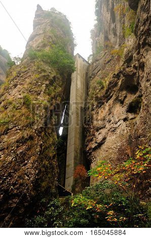 An elevator near Buddhist LingyanTemple in Yandangshan scenic area in between rock cliffs located in Zhejiang province of China on an overcast day.