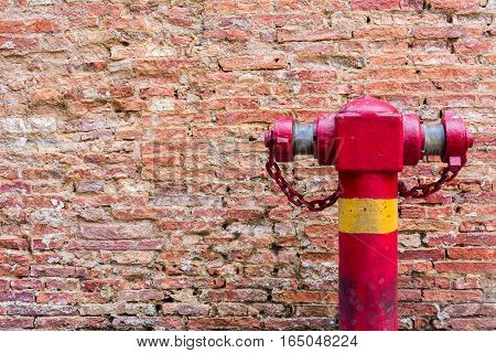 Fire Hydrant at the Weathered stained old dark brown Wall Dirty Brick Wall