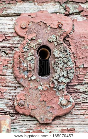 Old rusty decay cracked vintage red steel lock keyhole on a wooden door texture background