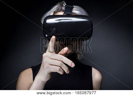 Woman wearing a futuristic looking virtual reality headset goggles. The device is technology that lets video gamers experience VR or AR augmented reality