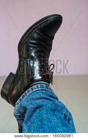 Close up men wear blue jean and brown leather shoes on floor.