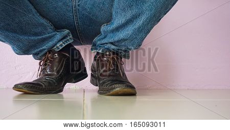 Close up men wear blue jean and brown leather shoes on floor.