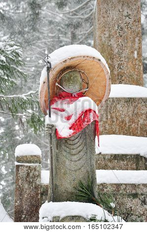 Jizo or stone statue wearing red apron under snow in Koyasan Japan
