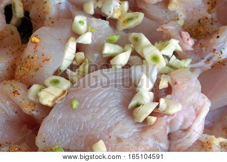 Sliced chicken meat with spice and garlic in cooking process closeup