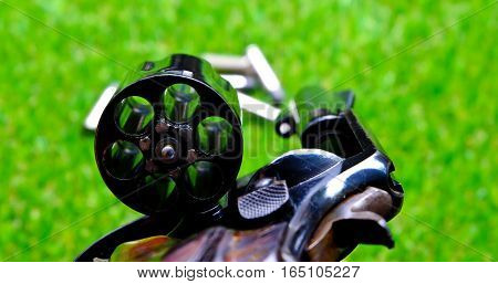 Revolver gun in hand on grass background