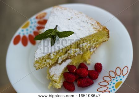 Cake, sponge cake with strawberry and green mint sprinkled with powdered