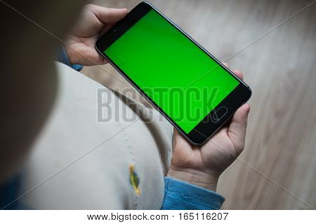 The child is holding a phone in his hand with a green screen for chroma keyer