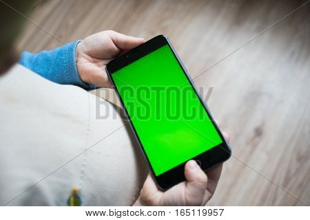 The child is holding a phone in his hand with a green screen for chroma keyer