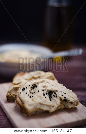 Sandwiches with hummus on the wooden board.