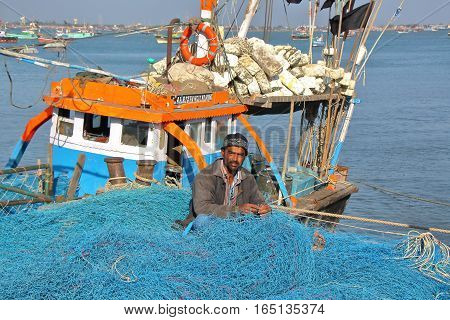 DWARKA, GUJARAT, INDIA - DECEMBER 26, 2013: Fisherman working on his fishing net in Bet Dwarka Island near Dwarka