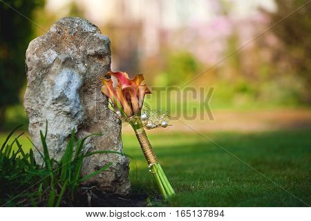 bouquet calla lilies near big stone on nature background