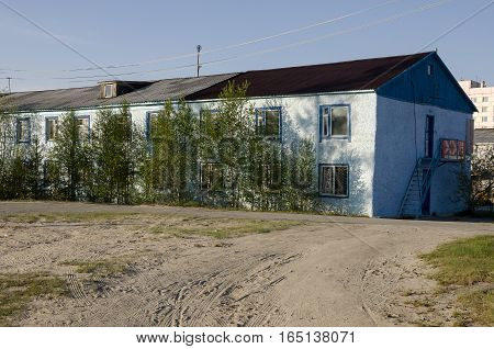 Blue misery and poor two-storeyed building with trees around