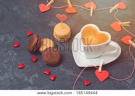 Valentines day concept with heart shape coffee cup and macarons over blackboard background